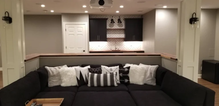 Basement media lounge with sectional sofa and herringbone tile wet bar
