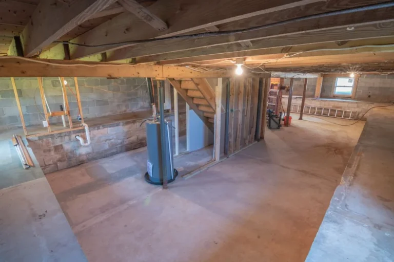 Empty unfinished basement with exposed beams, pipes and concrete flooring