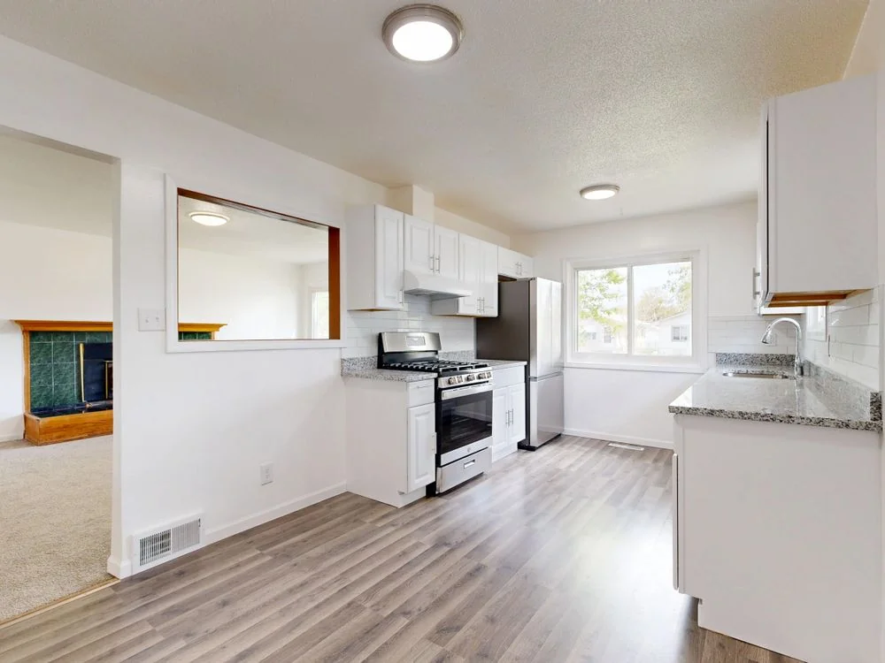 Renovated kitchen with white cabinets and hardwood flooring